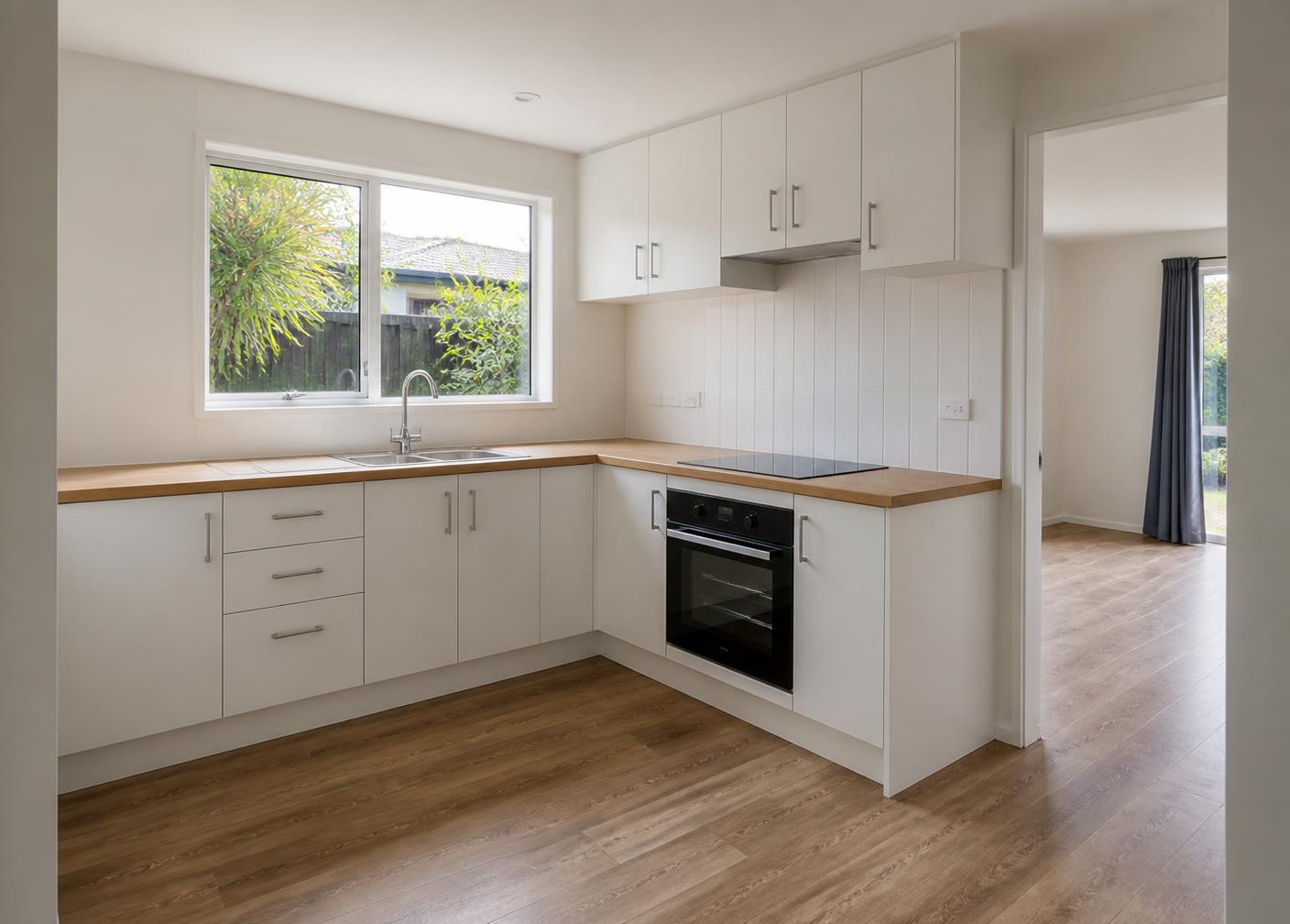 A finished kitchen fitout in a Christchurch do up: white cabinetry, timber benchtop and vinyl plank flooring